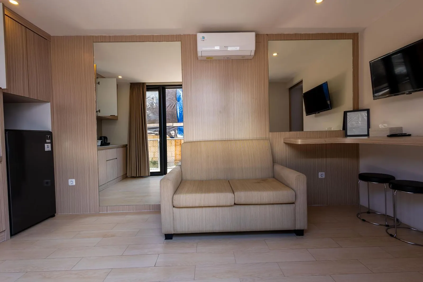 Deluxe Suite: sofa, writing desk and the kitchenette wall in pale oak