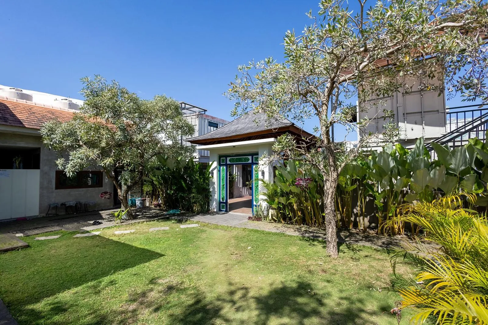 The full garden: lawn, tropical planting and the pavilion beneath the trees