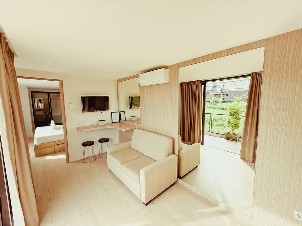 Suite living room in light wood with a sofa and doors open to the greenery
