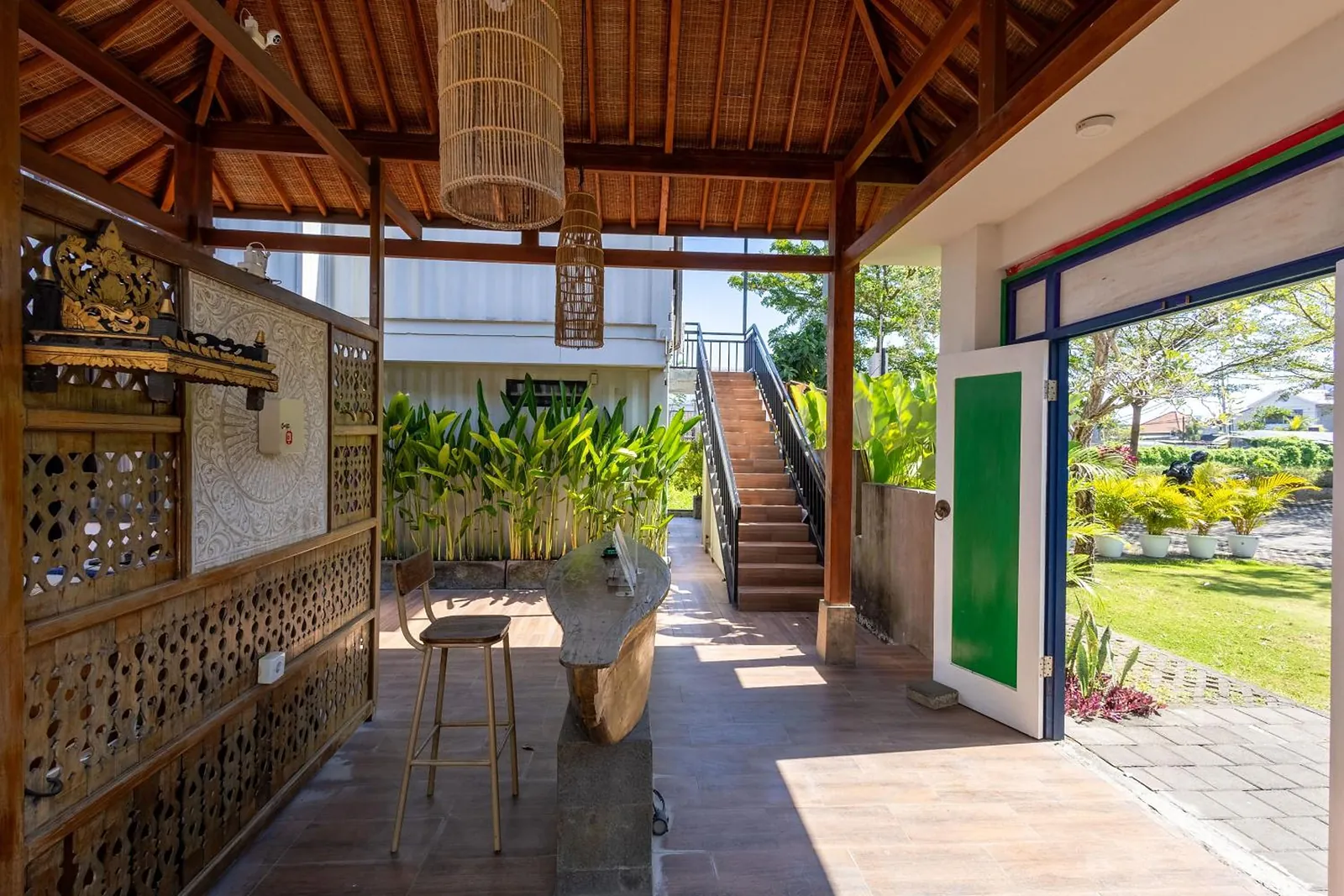 The pavilion's carved panels, rattan lamps and the stair up to the suites